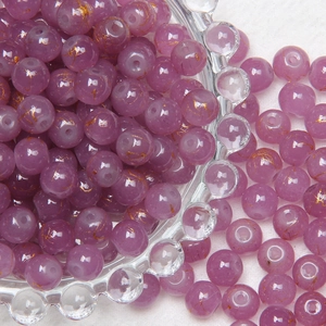 Close-up of 8mm purple glass beads with gold sand finish overflowing from a glass bowl