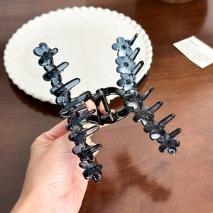 French vintage large black translucent floral hair claw clip held over a wooden table