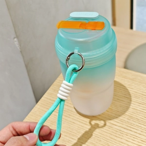 Detail of teal gradient portable plastic cup with woven handle and secure orange buckle