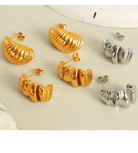 Detailed view of gold and silver textured spiral stud earrings in a minimalist layout