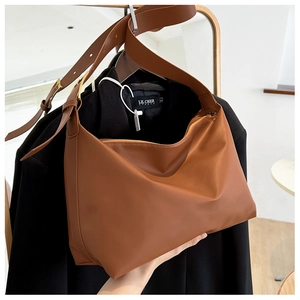 Detail of caramel brown leather tote bag showing textured finish and casual shoulder strap