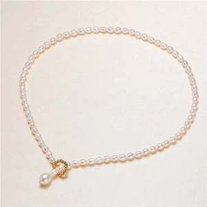 Close-up of elegant white pearl necklace with gold-plated swan pendant accessories