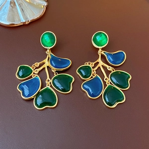Detailed view of floral vintage earrings with green and blue enamel on gold metal