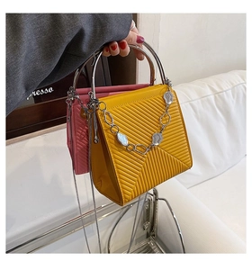 Close-up of quilted fashion handbags with silver circular handles and metal chain details