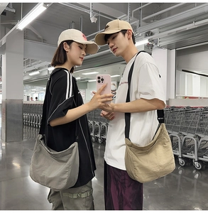 Waterproof nylon messenger bags in grey and khaki shown in a lifestyle street setting