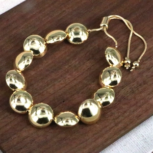 Dettaglio del bracciale a perle dorate con grani ovali in metallo e chiusura a scorrimento