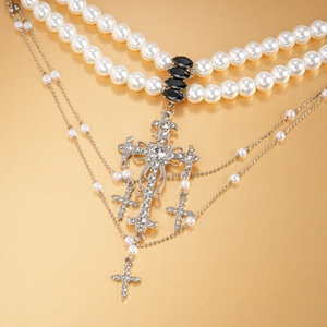 Detail of layered pearl necklace with rhinestone-encrusted cross and black gem charms