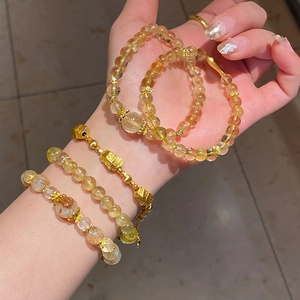 Close-up of a stacked yellow crystal bead bracelet set with golden flower charms