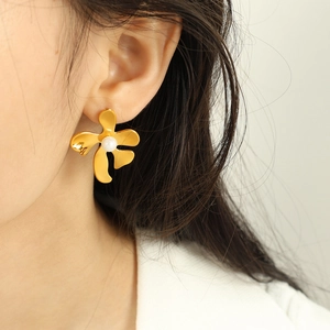 Boucles d'oreilles fleurs dorées irrégulières avec perles blanches portées avec style