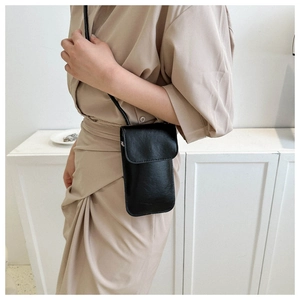Close-up of a stylish black leather crossbody phone bag worn with a beige dress