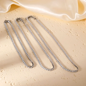 Three layered silver tennis necklaces with sparkling zircon stones on champagne silk fabric