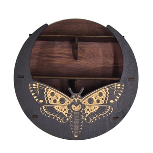Detail of bohemian wooden crescent moon shelf featuring a carved moth design on dark wood