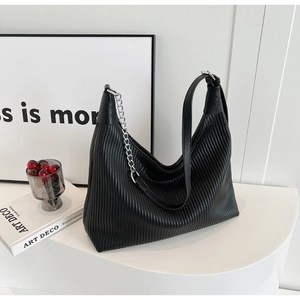 Détail d'un sac Hobo noir avec texture à rayures verticales et chaîne argentée chic