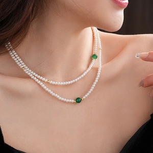 Close-up of double-layer white pearl necklace with green agate beads on neck