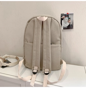 Detailed rear view of beige canvas backpack showing durable straps and texture on white table