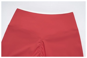 Vue macro du short de yoga rouge avec taille en V et liseré blanc contrastant