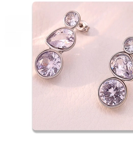 Macro detail of silver drop earrings with triple-set sparkling zircon stones