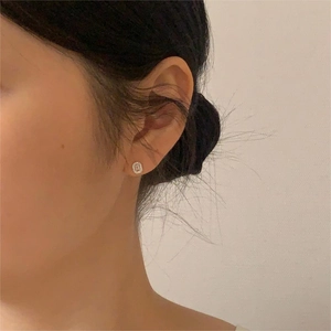 Close-up of geometric sterling silver stud earrings with crystals on female model