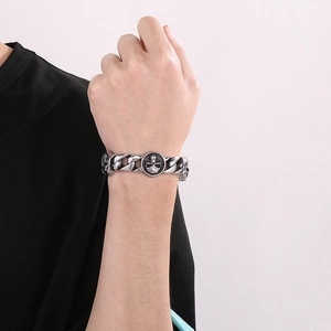 Macro detail of retro cuban chain bracelet featuring a round skull relief charm
