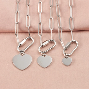 Three silver heart pendant necklaces with carabiner clasps on pink fabric background