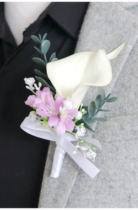 Close-up of a white calla lily boutonniere with silk ribbon on a grey suit lapel