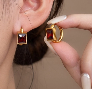 Detail of vintage gold-plated C-shape earrings featuring rectangular red gemstone accents