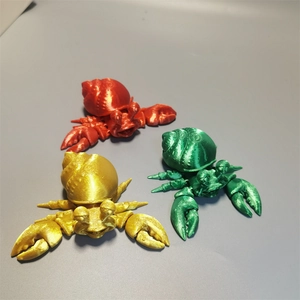 3D printed hermit crab toy figures in vibrant red, gold and green colors in a top view