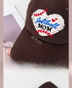 Close-up of heart embroidery on vintage brown baseball cap with worn edge detail