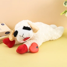 Close-up of white plush sheep with black patches and red heart button for sound features