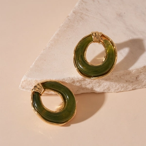 Close-up of vintage resin round earrings with gold metal frame and dark green shimmer