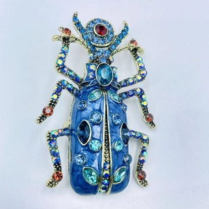 Dettaglio macro della spilla coleottero in smalto blu con strass e cornice dorata