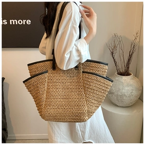 Detail view of large straw woven tote bag with premium black leather shoulder straps