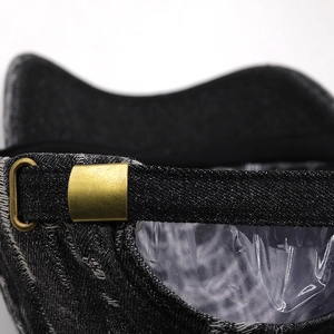 Close-up of adjustable strap with vintage brass buckle on denim baseball cap