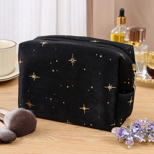 Close-up of black velvet cosmetic bag with gold stars on a wooden desk with brushes