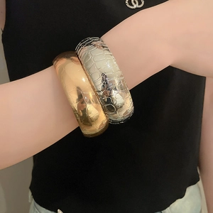 Close-up of wide metallic cuffs in gold and silver with textured crocodile skin patterns