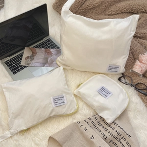 Detailed view of three white waterproof travel organizers with yellow zippers on plush rug