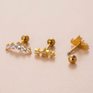 Goldene Edelstahl-Ohrstecker mit Zirkonia-Sternen und Kronen auf rosa Hintergrund