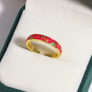 Macro detail of golden flower ring with red enamel petals on a jewelry box cushion