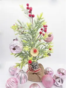 Detail of pink Christmas ornaments and small artificial pine tree with burlap base