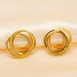 Detailed view of triple-intertwined gold hoops on champagne silk background