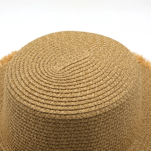 Detail of natural woven straw boater hat featuring fine texture and fringed brim edges