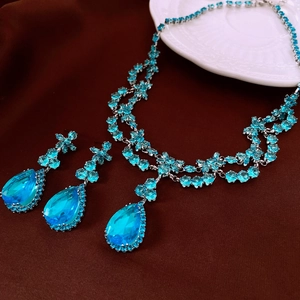 Détail d'un ensemble de bijoux en argent avec pierres gouttes en zircon bleu sur tissu