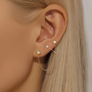 Close-up of S925 silver star earrings with gold plating and zircons on model ear