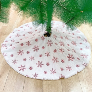 Detail eines weißen Plüsch-Weihnachtsbaumrocks mit roten Pailletten-Schneeflocken