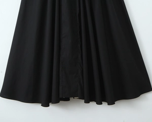 Detail of flowing black pleated skirt hemline with soft drape and delicate fabric texture