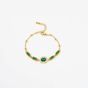 Macro shot of gold bracelet with oval and rectangular emerald-green zircon stones