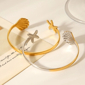 Detail of gold and silver open bracelets featuring seashell and starfish oceanic designs