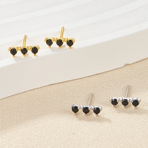 Detail view of gold and silver bar earrings with three black round-cut zircons set in a row