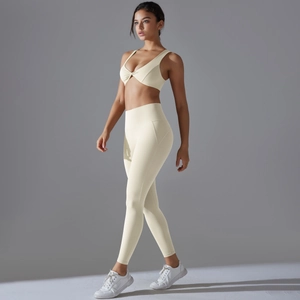 Sleek beige two-piece yoga set featuring twist-front sports bra and high-waisted leggings