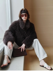 Detail of dark brown faux fox fur cashmere vest texture on model in minimalist setting